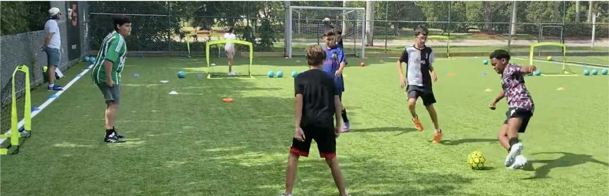 A group of children play soccer on an outdoor field